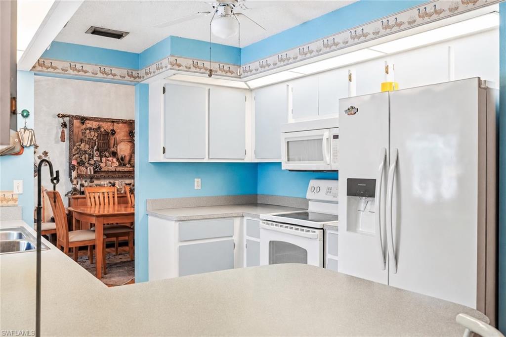 VIRTUALLY STAGED Kitchen featuring white cabinetry, light countertops, and a white appliance suite including a side-by-side refrigerator