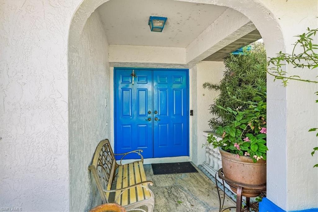 Arched entryway featuring vibrant blue double doors with paneled detailing