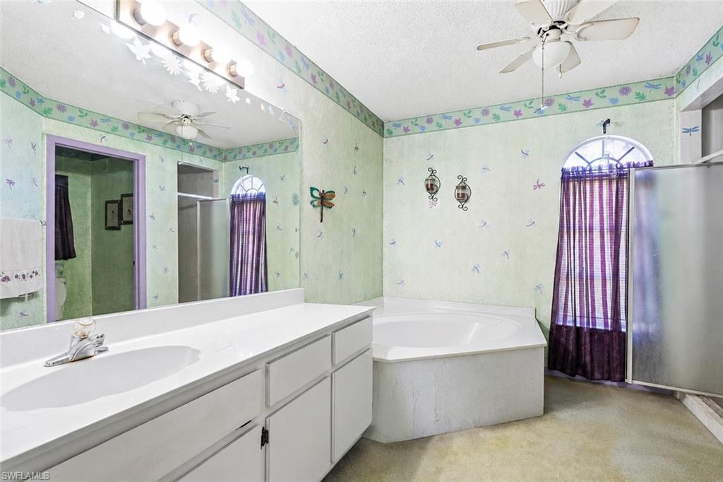 VIRTUALLY STAGED Double vanity with integrated sinks and white cabinetry, accompanied by a corner soaking tub and a separate shower enclosure