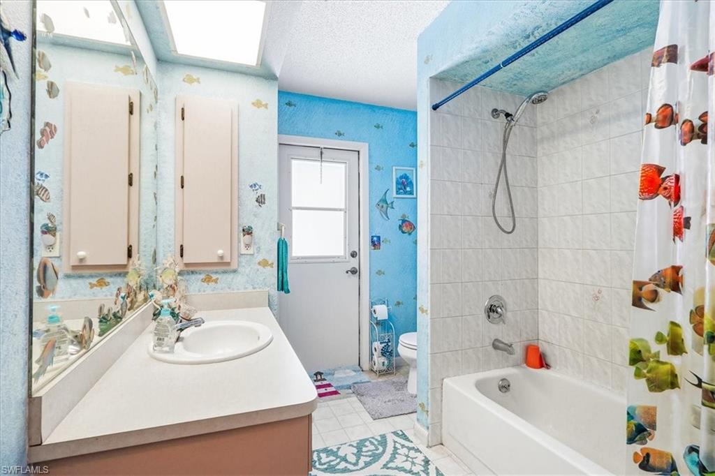 Bathroom featuring a single vanity, built-in storage cabinets, a combination shower and tub, and a windowed exterior door