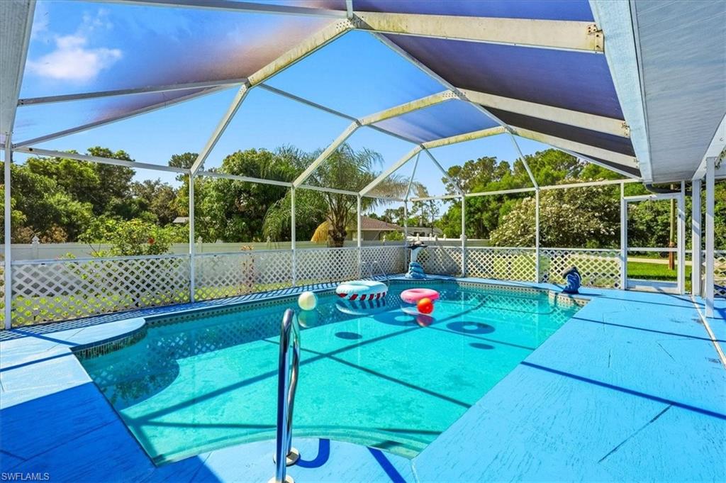 Screened swimming pool enclosure featuring a patterned blue deck and white lattice fencing