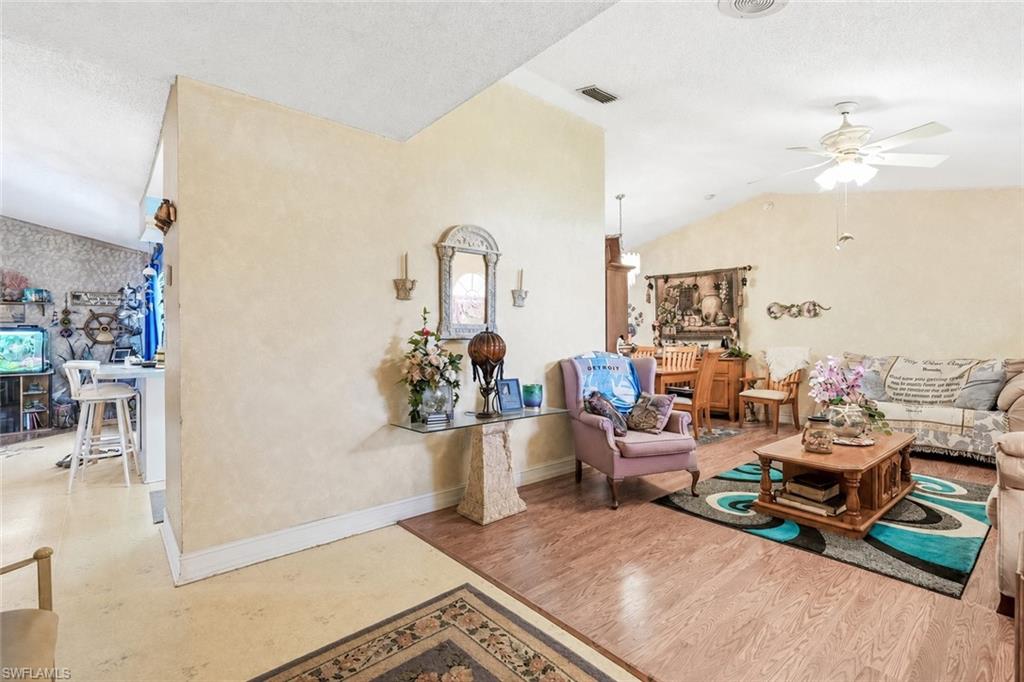 Spacious living area featuring wood-finish flooring, vaulted ceilings, and a ceiling fan with light fixture