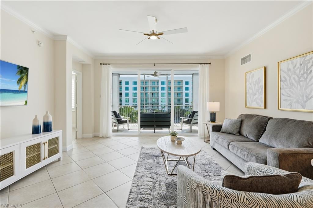 Living area featuring light-colored tile flooring, crown molding, and a ceiling fan