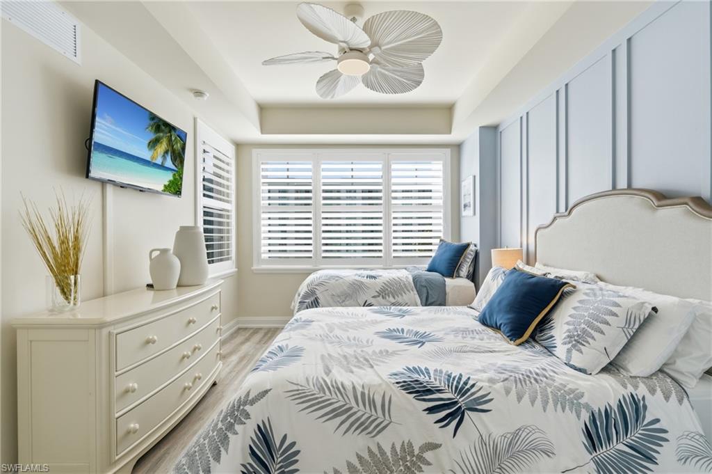 Room featuring two beds, a mounted television, and plantation shutters