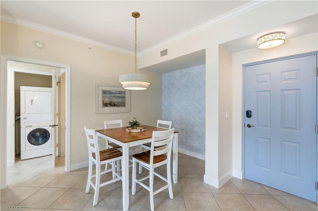 Dining area featuring tile flooring, a contemporary drum pendant light, and a dedicated laundry closet with a stacked washer and dryer