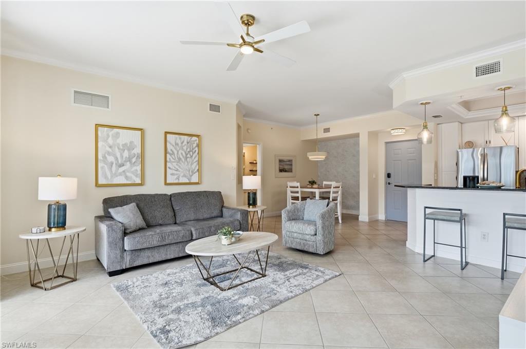 Open-concept living area featuring tile flooring, crown molding, a ceiling fan with integrated lighting, recessed lighting, and a kitchen island with pendant lighting