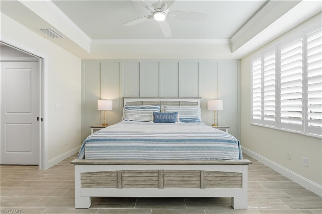 Recessed ceiling lighting, tray ceiling, wood-finish flooring, plantation shutters, and a ceiling fan with integrated lighting