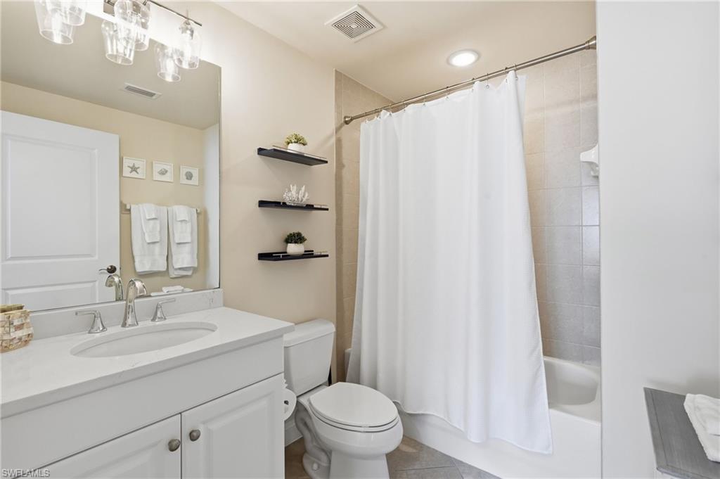 Bathroom featuring a white vanity with an undermount sink, a large wall mirror, and a combination tub and shower with tiled surround
