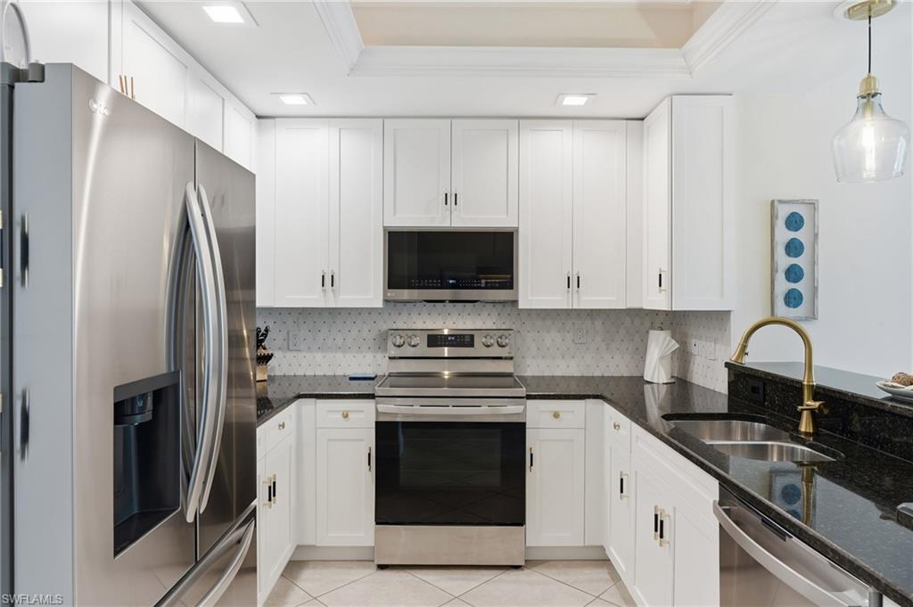 U-shaped kitchen with white cabinetry, dark stone countertops, stainless steel appliances, a tile backsplash, and recessed lighting