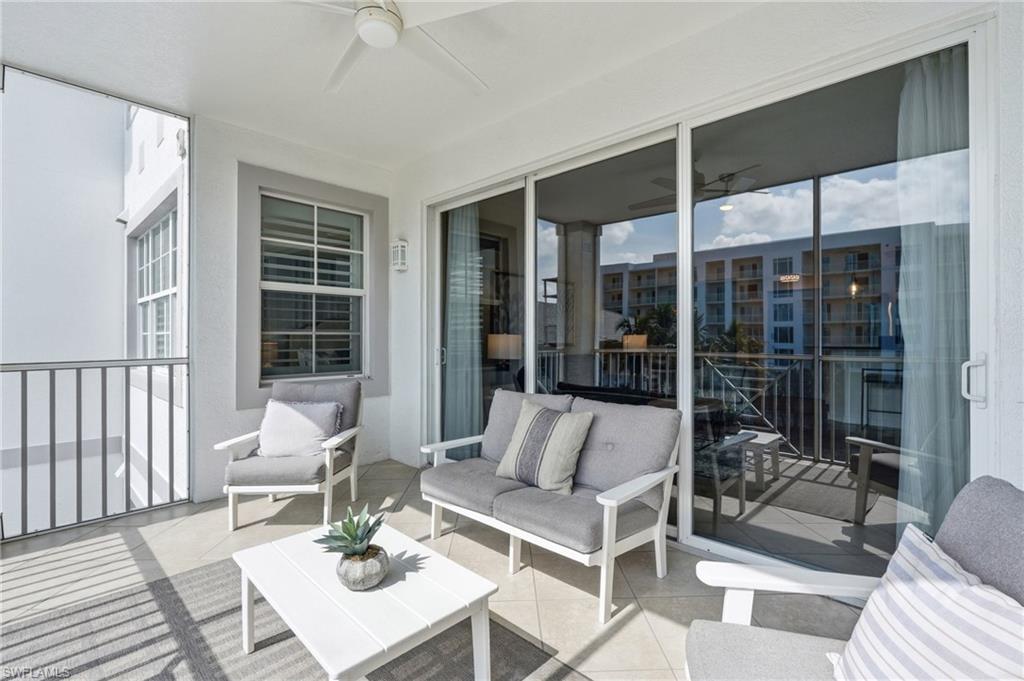 Covered balcony featuring a ceiling fan, sliding glass doors, a window with horizontal blinds, and a metal railing