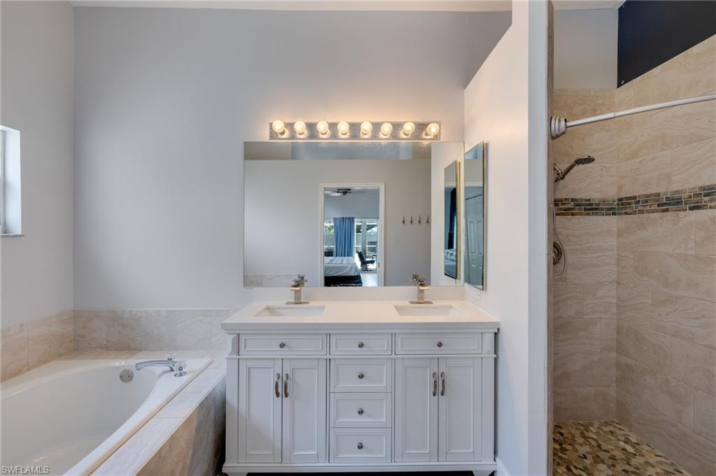 Dual vanity with white cabinetry and integrated sinks, a large mirror, and overhead vanity lighting