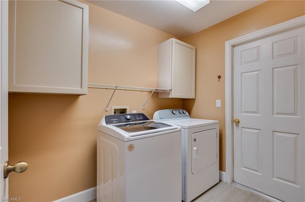 Dedicated laundry area featuring overhead cabinetry, wall-mounted shelving, and wood-finish flooring