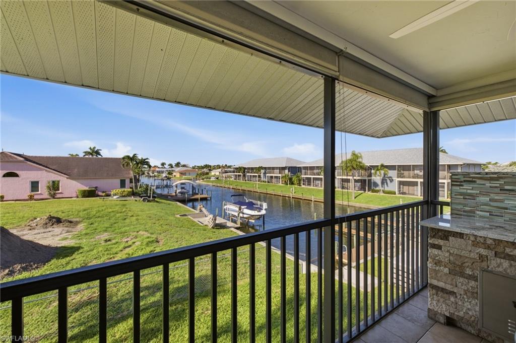 Screened balcony featuring a built-in outdoor kitchen with a stone facade, granite-style countertop, and a mosaic tile backsplash