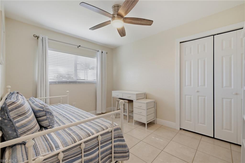 Room featuring tiled flooring, a window with blinds and drapes, a ceiling fan with integrated lighting, and a closet with bifold doors
