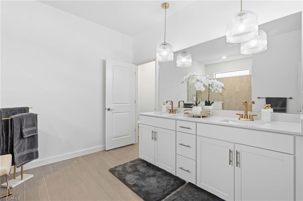 Dual vanity featuring white cabinetry with brushed gold hardware, undermount sinks, and light-toned countertops