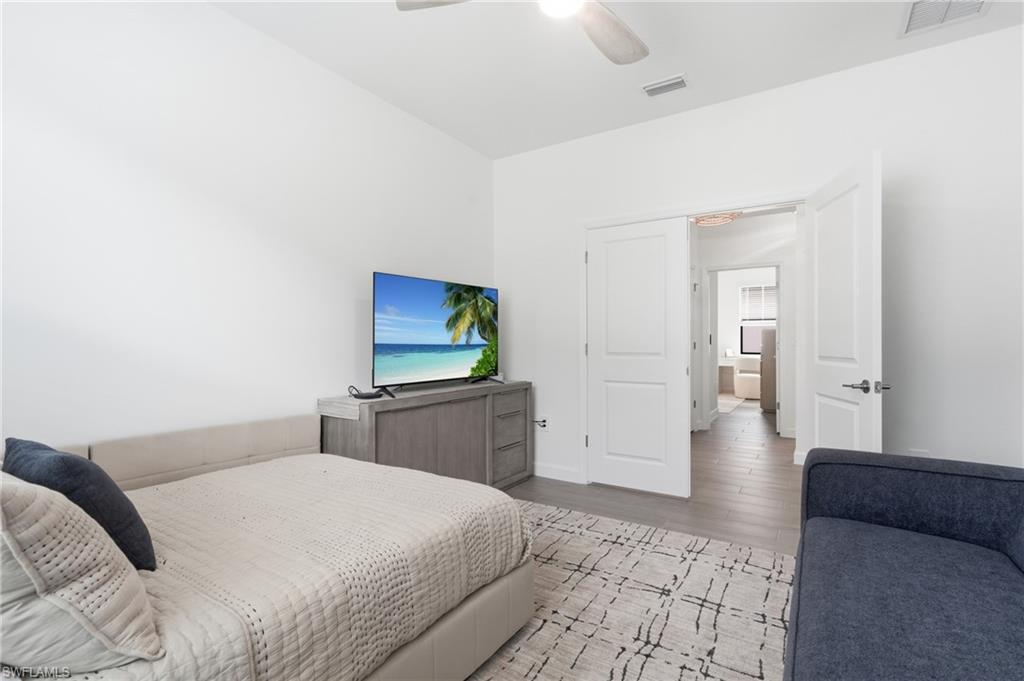 Spacious room with light wood-finish flooring, white walls, and a ceiling fan