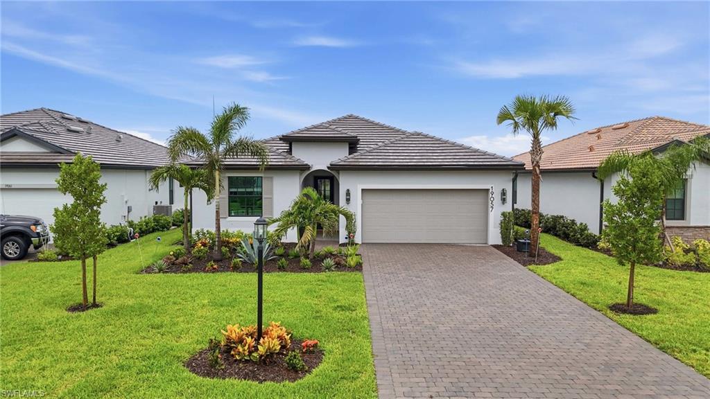 Contemporary single-story residence featuring a tile roof, stucco exterior, and an integrated two-car garage