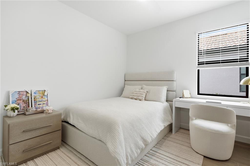 Bright room featuring a window with horizontal blinds, a neutral color palette, and light wood-finish flooring