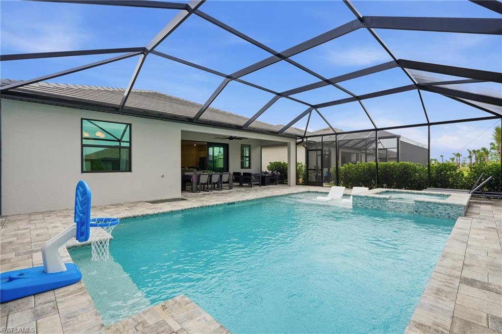 Screened lanai featuring a rectangular swimming pool with integrated spa and sun shelf