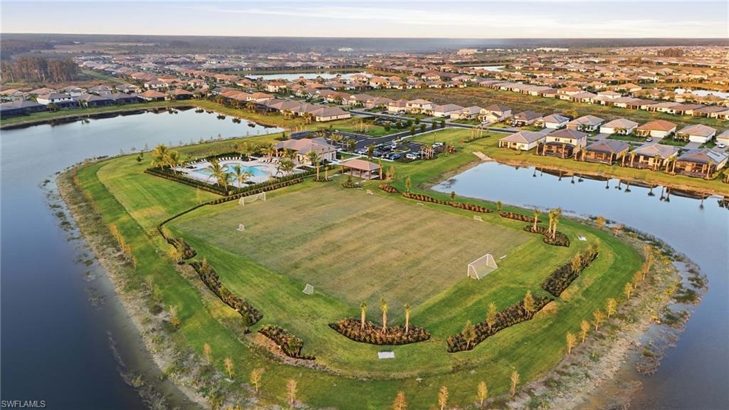 Expansive community green space with a large central field, surrounded by tranquil water features