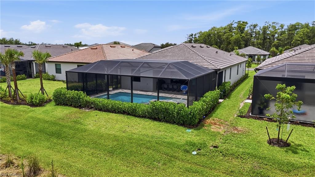 Screened swimming pool enclosure with a paved deck, surrounded by manicured landscaping