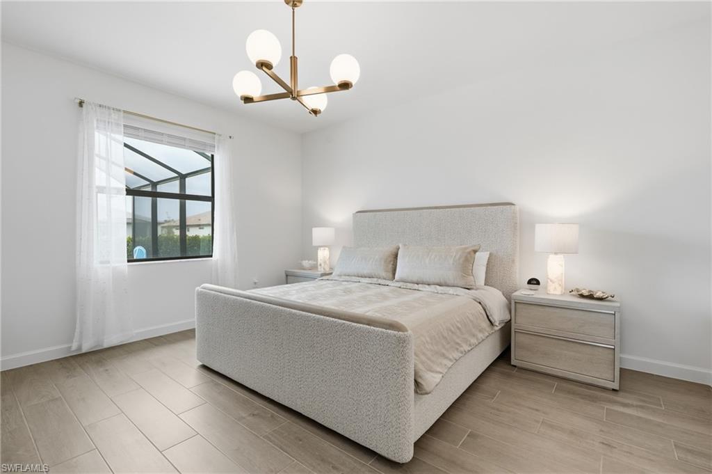 Bright interior featuring wood-finish flooring, a contemporary chandelier, white walls, and a large window with sheer drapery