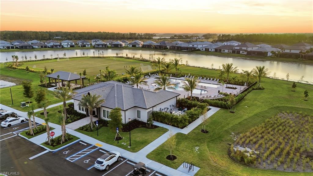 Community clubhouse featuring a swimming pool, lounge seating, and surrounding green spaces