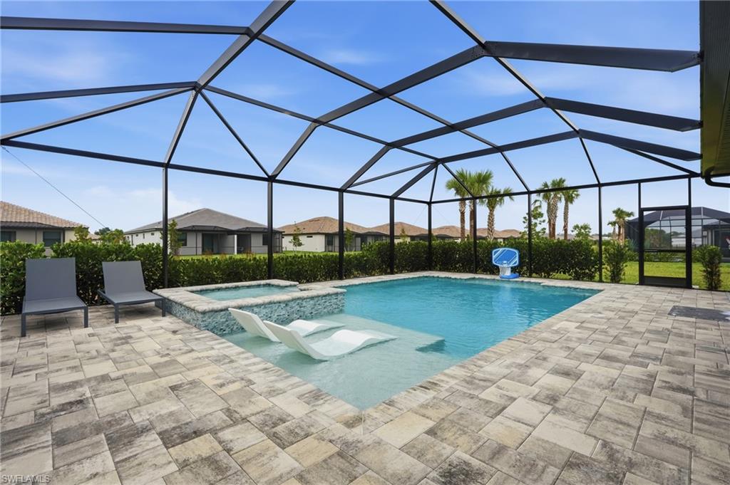 Screened-in outdoor area featuring a swimming pool, integrated spa, and spacious paver patio