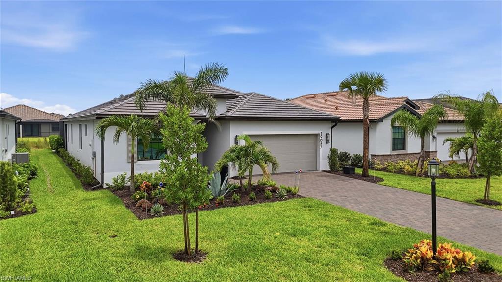 Contemporary single-story residence featuring a stucco exterior, tile roof, and a paver driveway