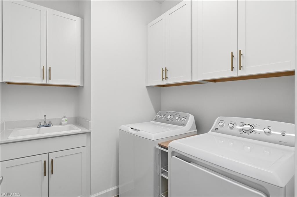 Laundry room featuring white shaker-style cabinetry, a built-in utility sink with a stone-finish countertop, and brass-finish hardware