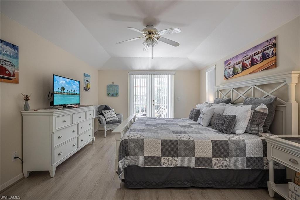 Bedroom featuring light wood finished floors, lofted ceiling, a ceiling fan, and baseboards