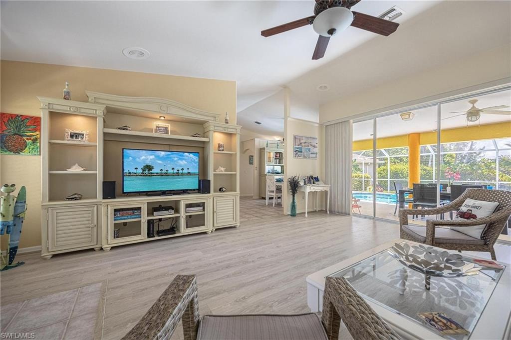 Living room with a ceiling fan, wood finished floors, and vaulted ceiling