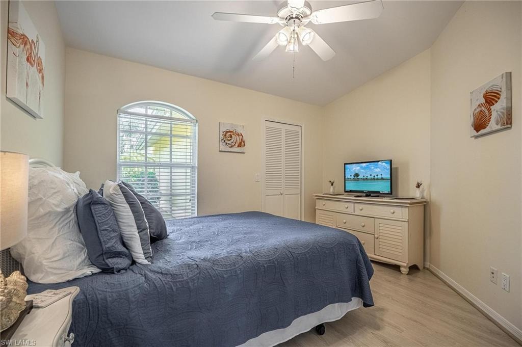 Bedroom featuring light wood-style floors, baseboards, a ceiling fan, lofted ceiling, and a closet