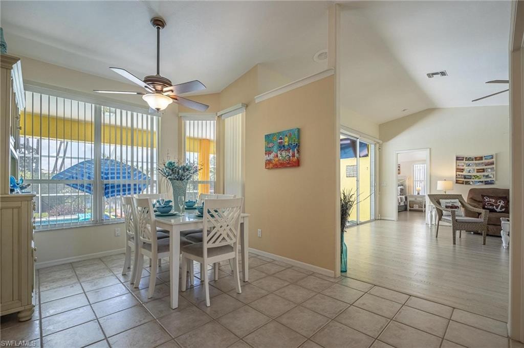Dining area with a ceiling fan, vaulted ceiling, plenty of natural light, light tile patterned flooring, and baseboards