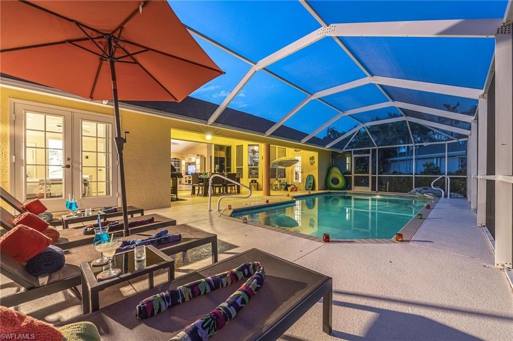 Swimming pool with french doors, a patio, outdoor lounge area, and glass enclosure