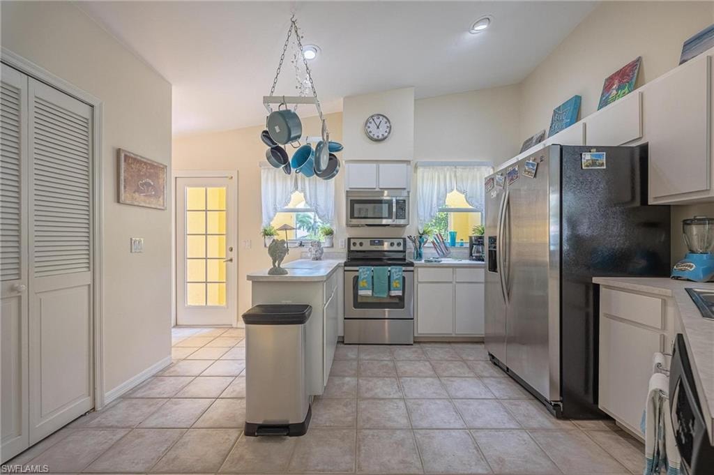 Kitchen with stainless steel appliances, light countertops, white cabinetry, and light tile patterned floors