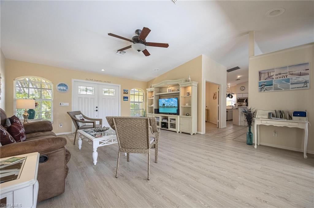 Living area with ceiling fan, lofted ceiling, light wood-style flooring, and baseboards