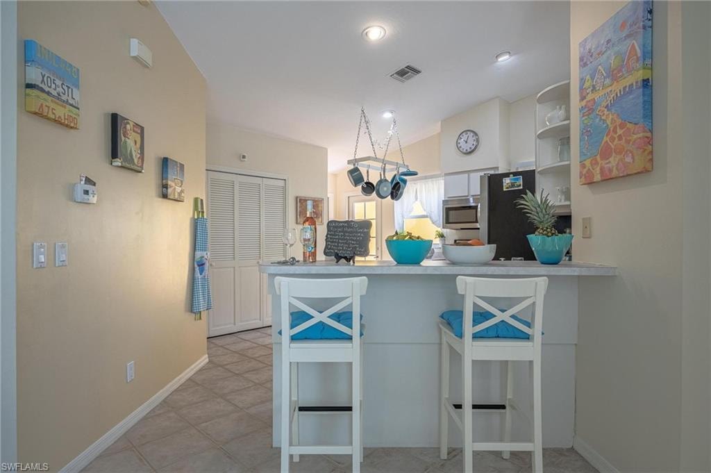 Kitchen with appliances with stainless steel finishes, a peninsula, baseboards, open shelves, and light countertops