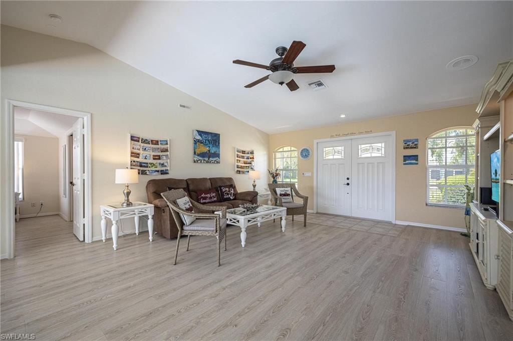 Living room with ceiling fan, light wood finished floors, vaulted ceiling, and baseboards