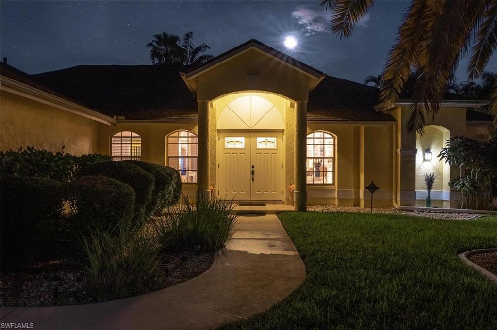 Exterior entry at twilight with stucco siding and a lawn