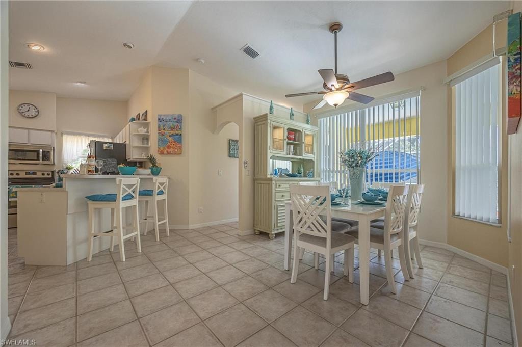 Dining room featuring a ceiling fan, light tile patterned flooring, baseboards, and vaulted ceiling