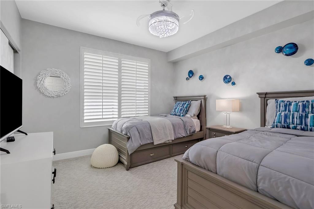 Bedroom with light colored carpet and hanging lights