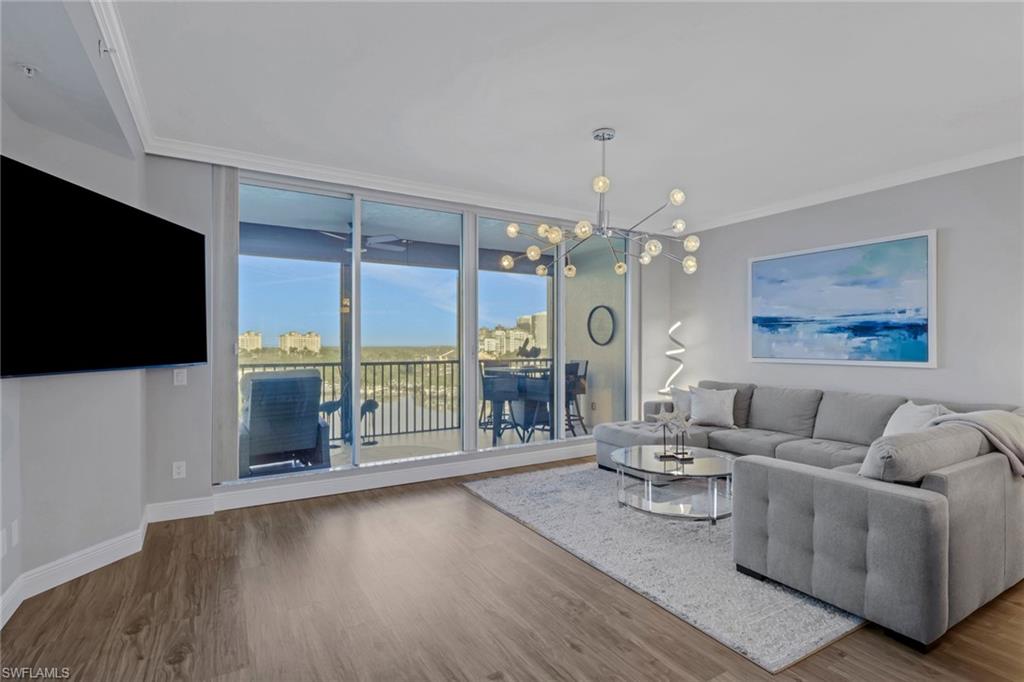 Living area featuring crown molding, wood finished floors, hanging lights, and floor to ceiling windows