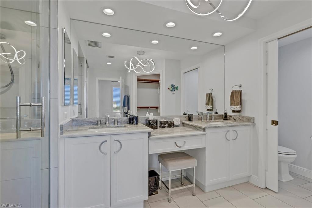 Bathroom with a stall shower, double vanity, a chandelier, and light tile patterned floors