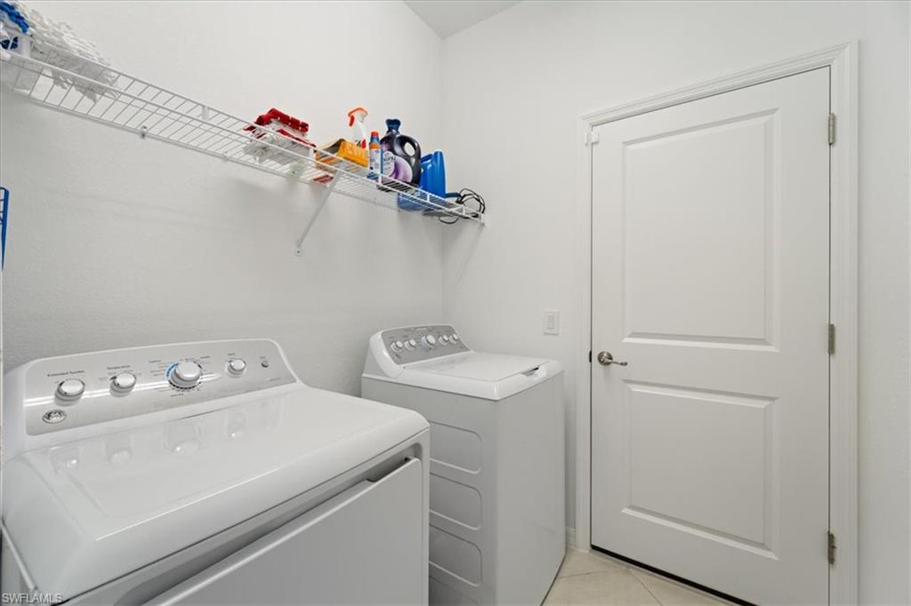 Dedicated laundry area featuring white walls, wire shelving, and a paneled door with a brushed nickel handle