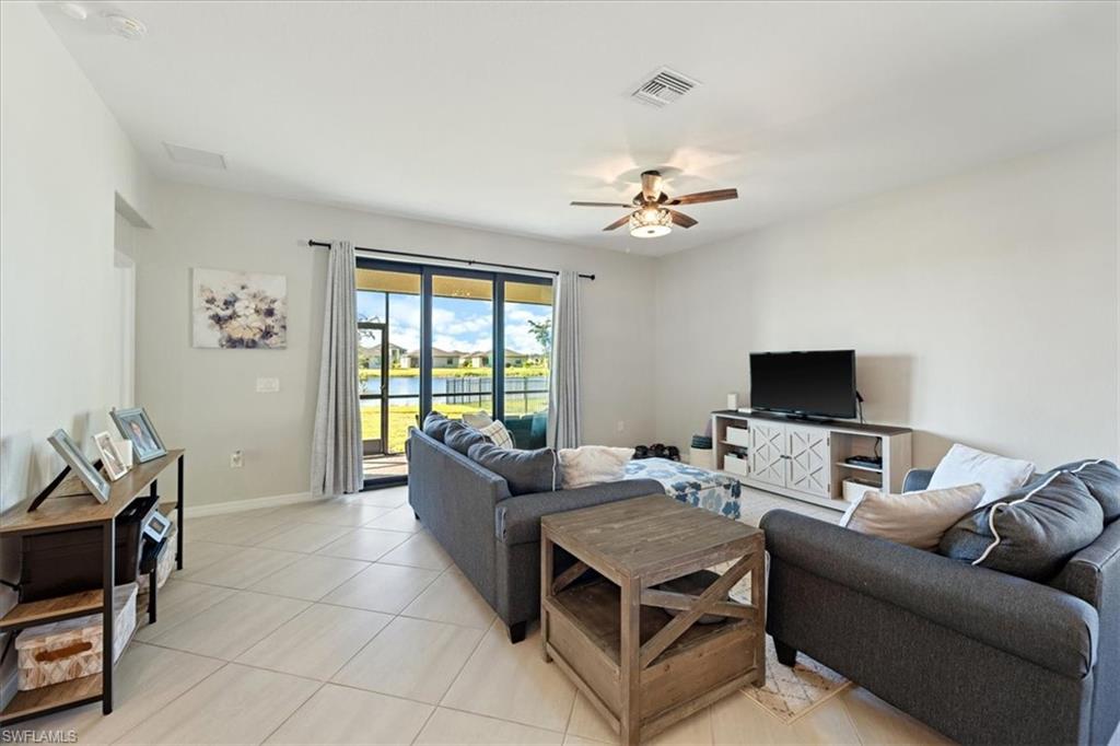 Spacious living area featuring light-toned tile flooring, recessed lighting, and a ceiling fan