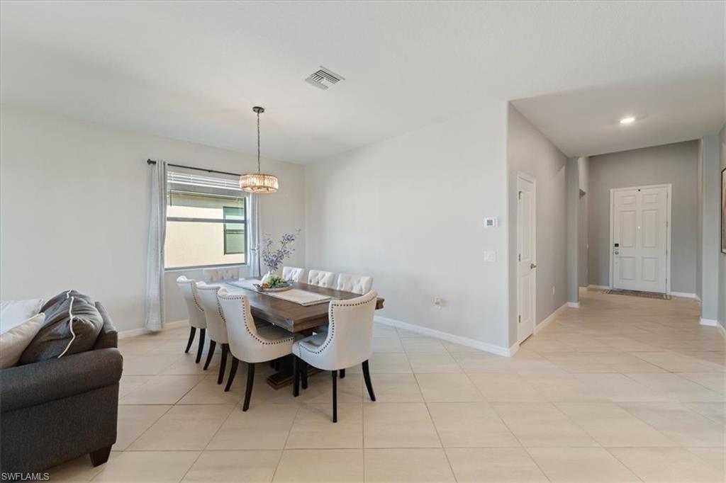 Spacious open-concept area featuring light-toned tile flooring, recessed lighting, and a modern chandelier