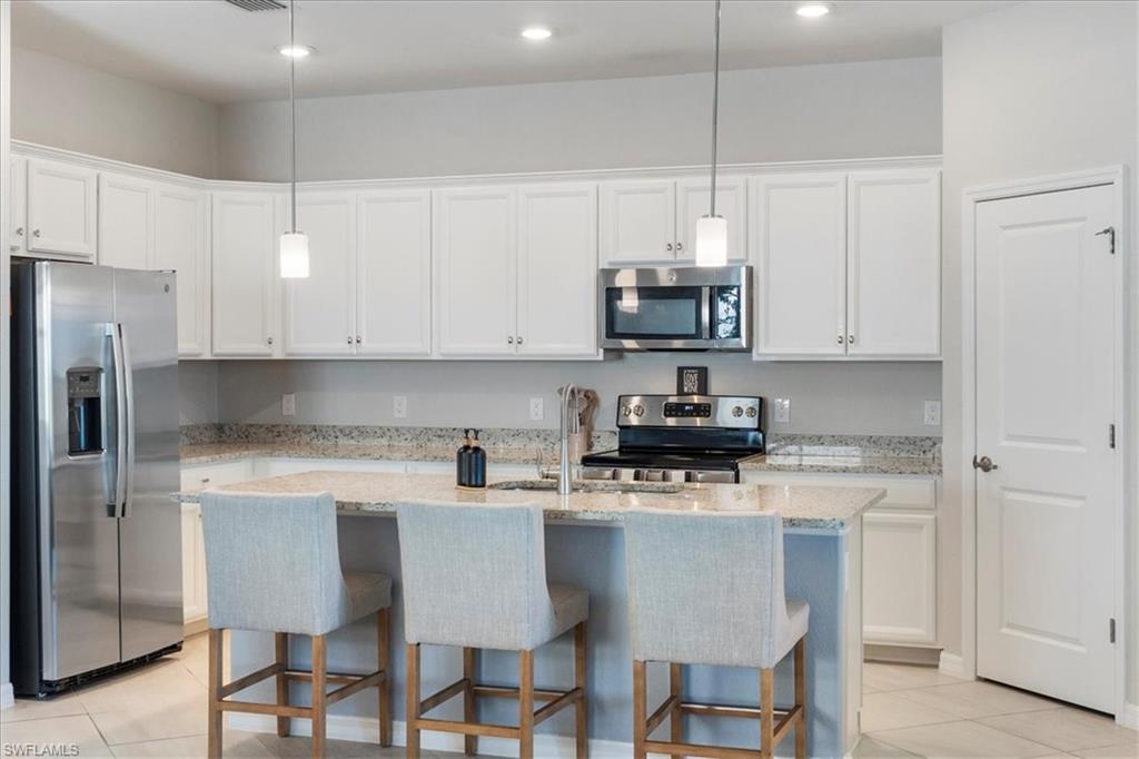 Kitchen featuring a central island with countertop seating, white shaker-style cabinetry, stainless steel appliances, recessed lighting, and pendant lighting