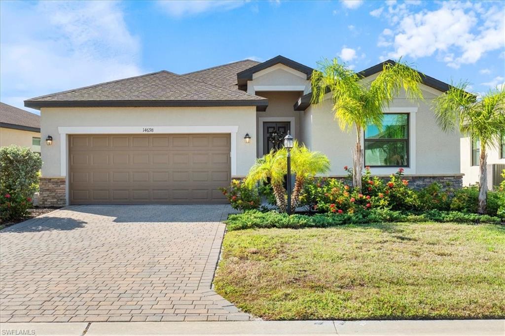 Contemporary single-story residence featuring a paver driveway, an integrated two-car garage, and a stucco exterior with stone accents