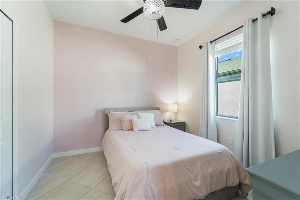 Room featuring neutral wall tones, a single window with blinds and drapes, tile flooring, and a ceiling fan with integrated lighting